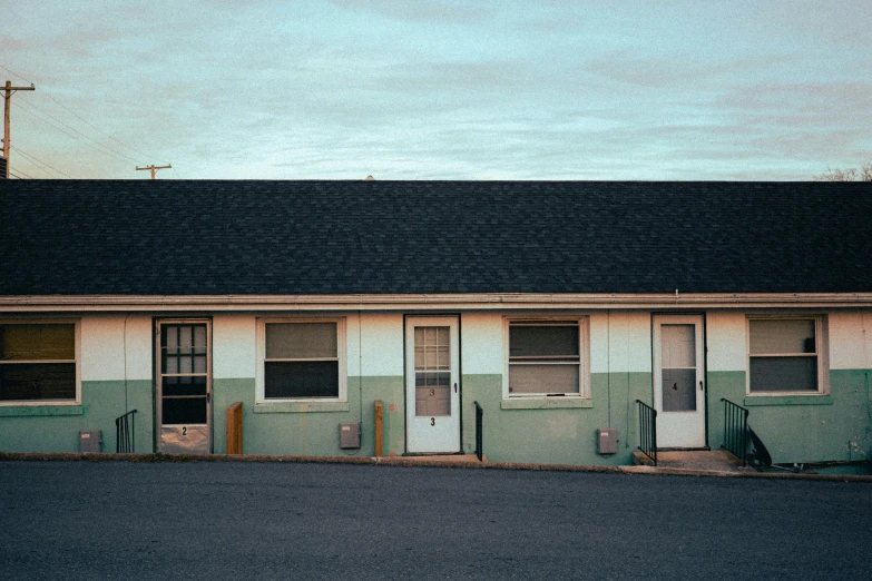 the outside of a motel with windows and door opened