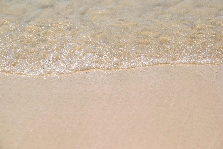 close up view of sand with wavy water on beach