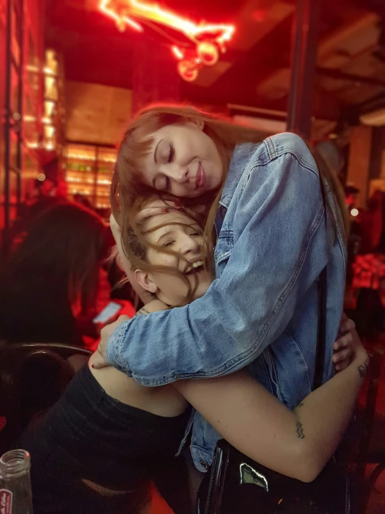 a girl that is hugging another girl in front of a bar