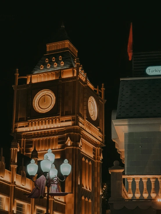 an elaborate clock tower sits next to a building lit up at night