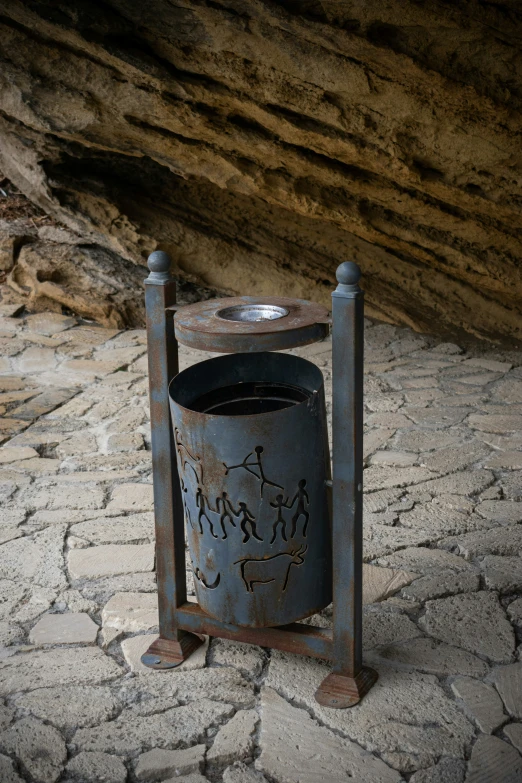 a blue metal trash can sitting on a cobblestone street