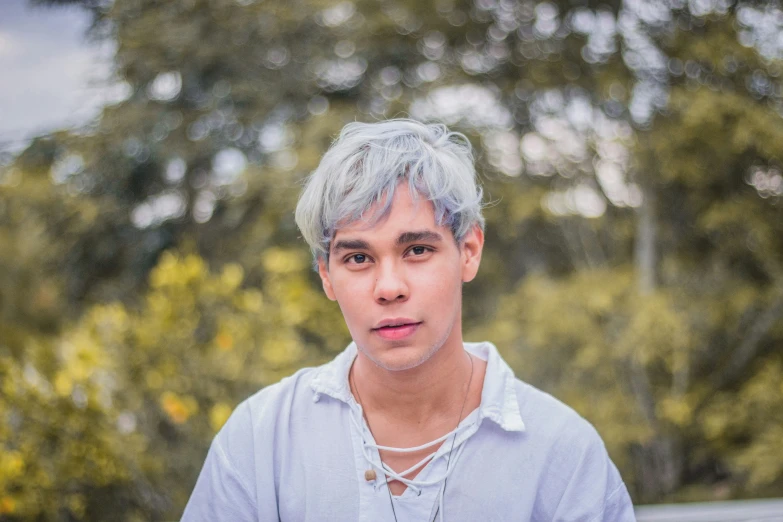 the young man has silver hair and is wearing a light blue shirt