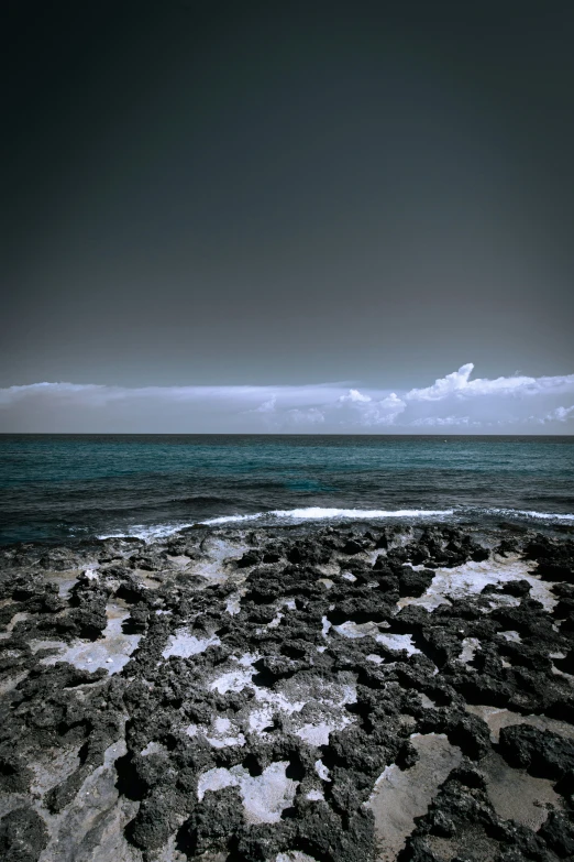 some rocks water clouds and a black sky