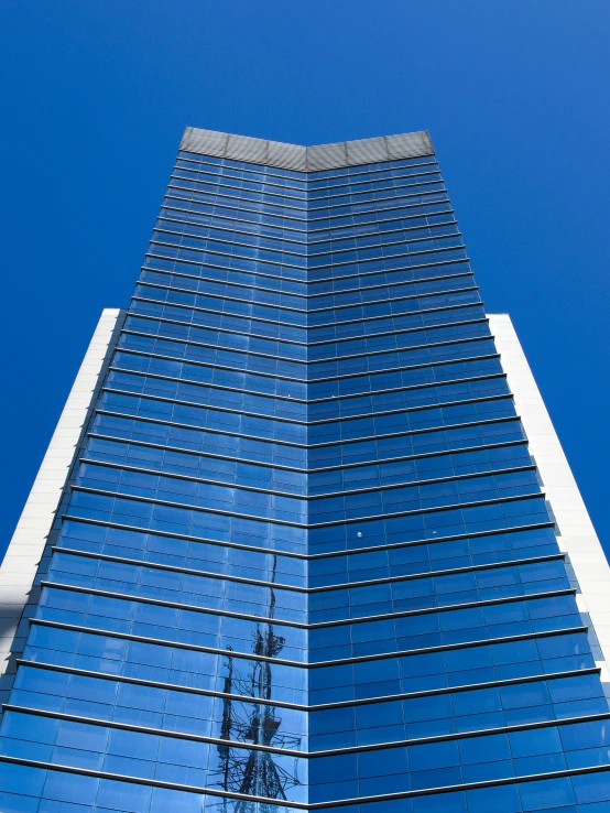 very tall building in an urban setting, reflecting the blue sky