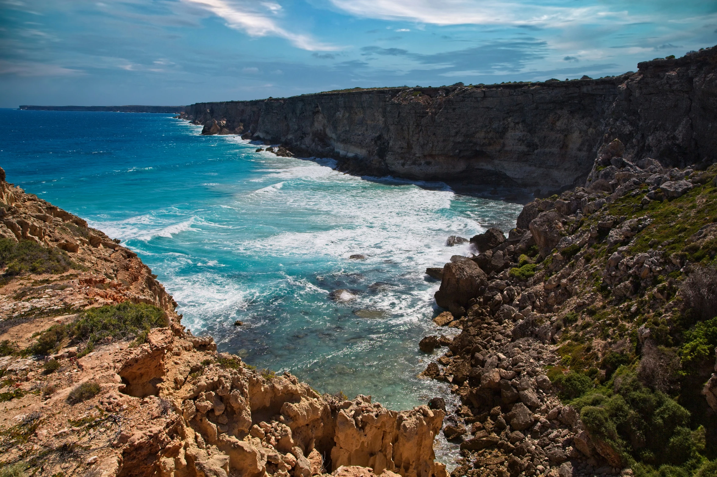 the shoreline has many layers of blue water and cliffs