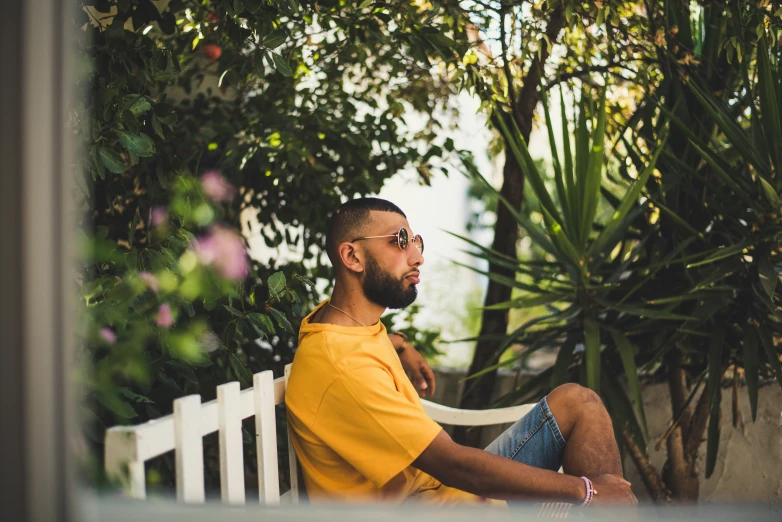 man in a yellow shirt sitting on white bench