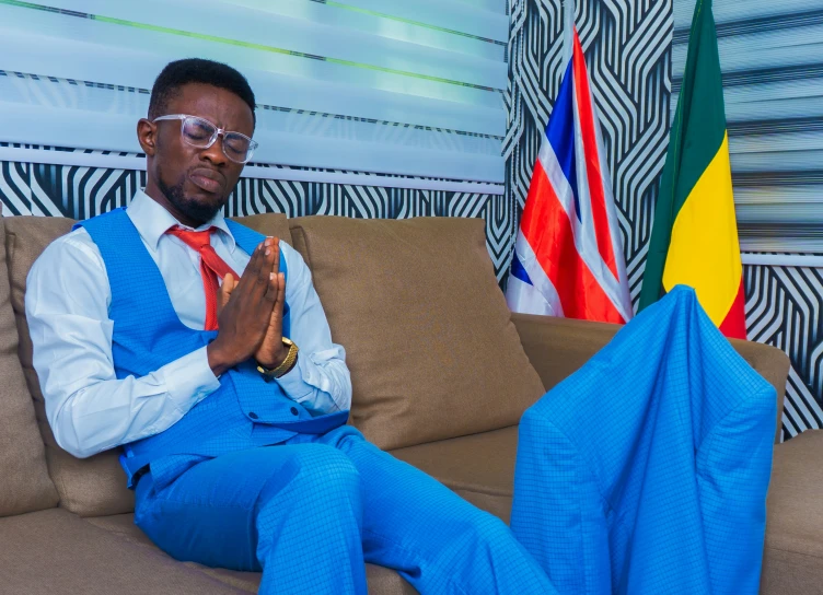 a person with glasses and blue pants sitting on a couch