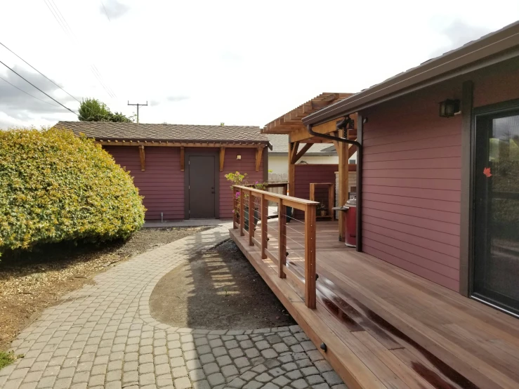 wooden patio steps leading to two house with brick walkway