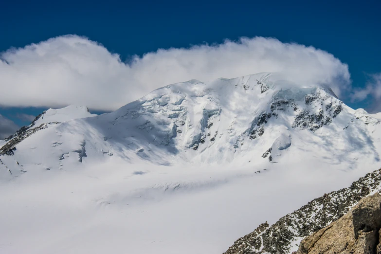 snow covered mountains with clouds above them