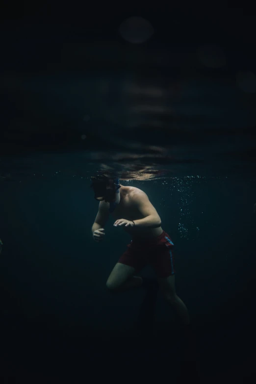 man standing in the dark water in swimming trunks