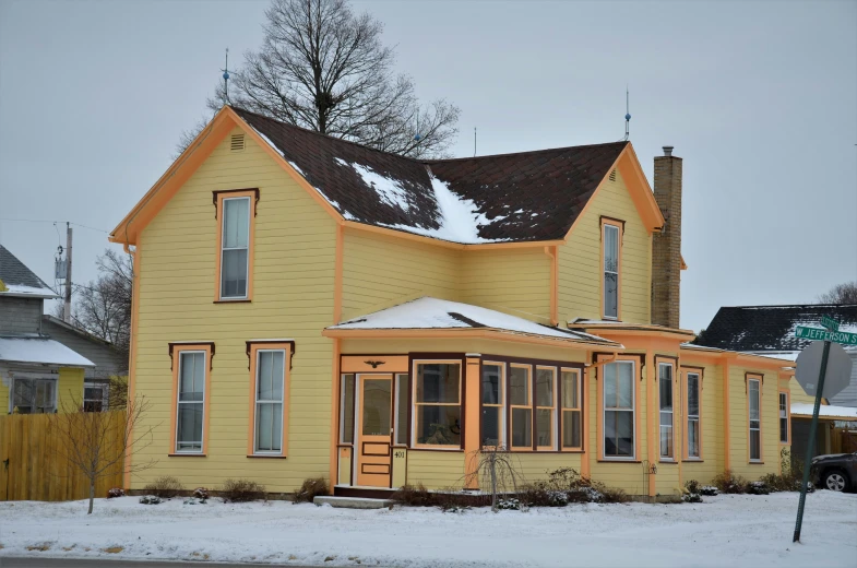 a yellow house with orange trim and brown roof