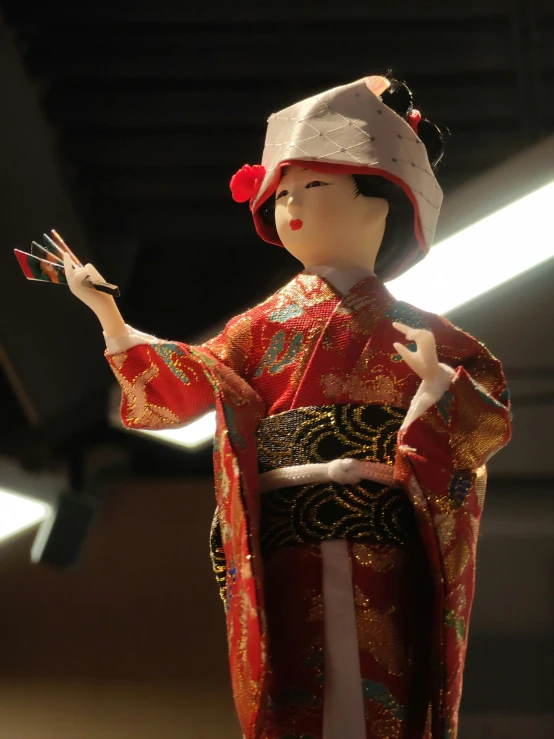 a doll in a traditional asian dress holding soing up