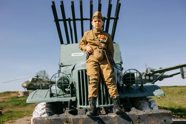 a man in an army outfit sitting on the back of a military vehicle