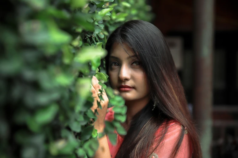 a woman in a red outfit standing near some plants