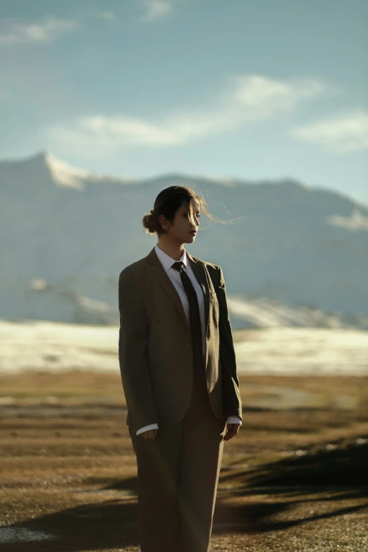 a woman in suit and tie standing on a desert plain