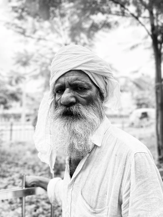 black and white pograph of an old man with grey hair and a scarf