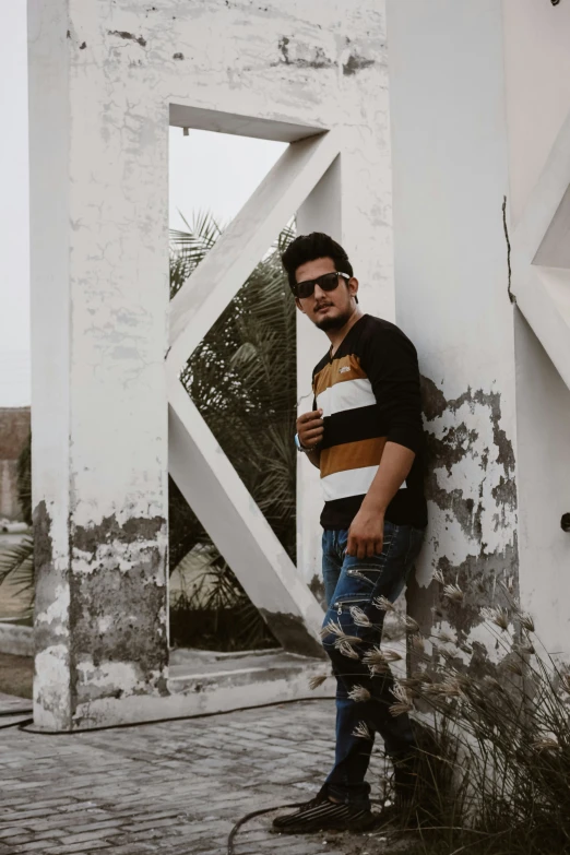 man wearing sunglasses leaning against an abandoned building