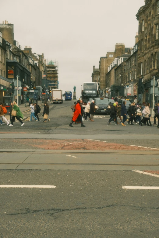 an intersection with people crossing and buses parked nearby