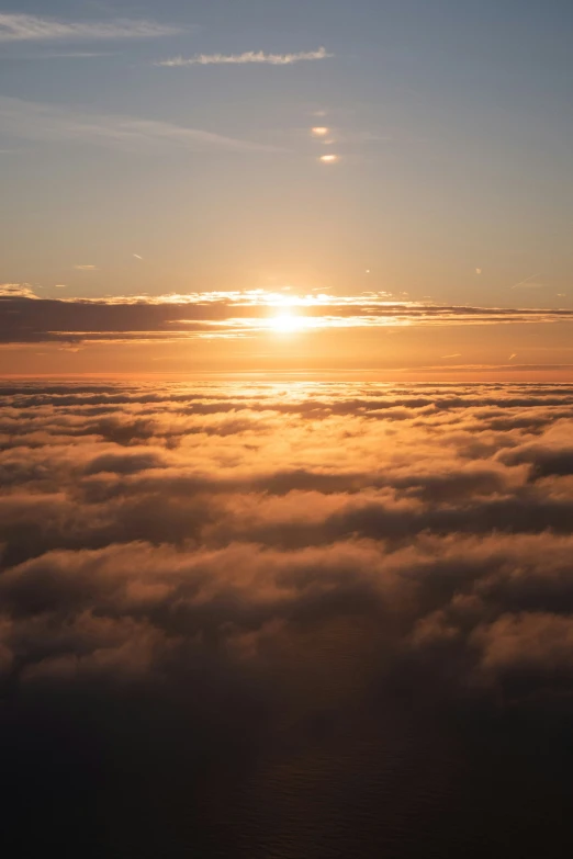 a sunset behind the clouds from an airplane