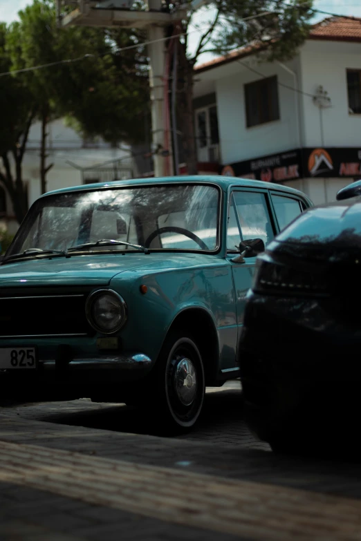 small light blue car driving down the street in the sun