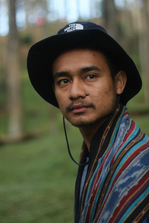 man with hat and ear buds on in the forest