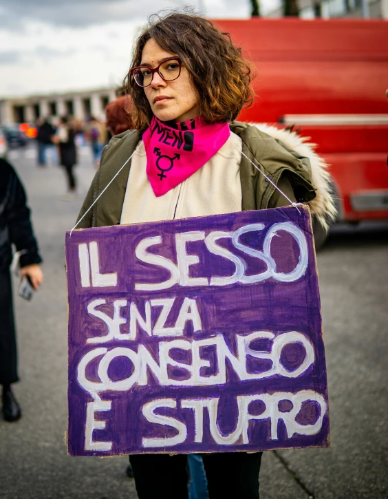 a woman in glasses holding a protest sign