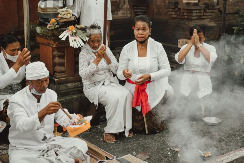 three women sit in a group around some smoke