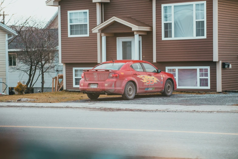 a small red car parked in front of some houses