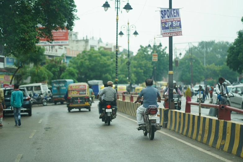 the man is riding his motorcycle while people walk in the street