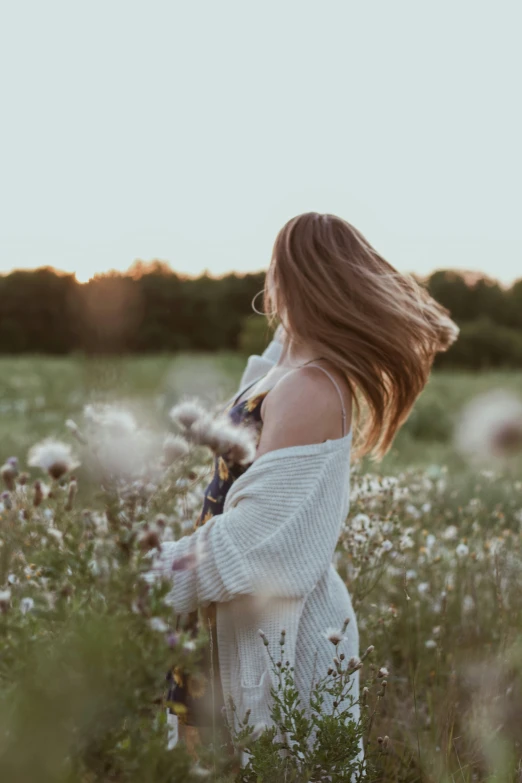 a woman in a field of grass holding flowers