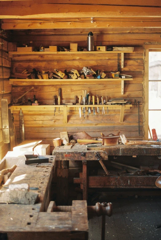 some tools are on a wooden table near wood shelves