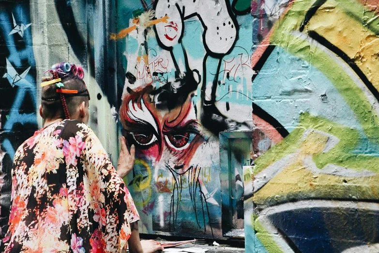 an older woman stands in front of a wall with colorful graffiti