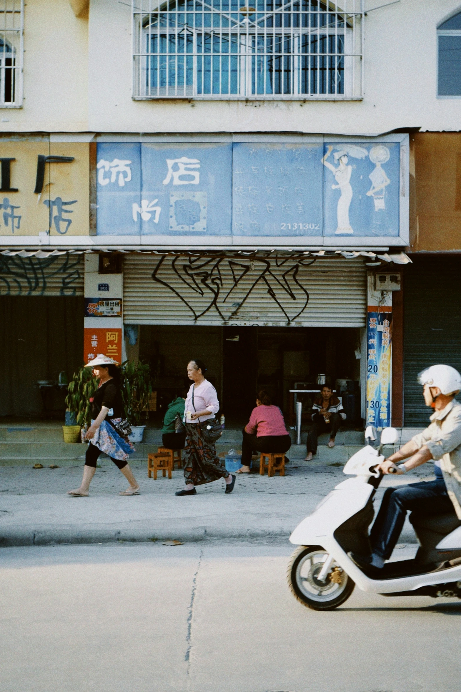 a man riding a white scooter down a street next to people