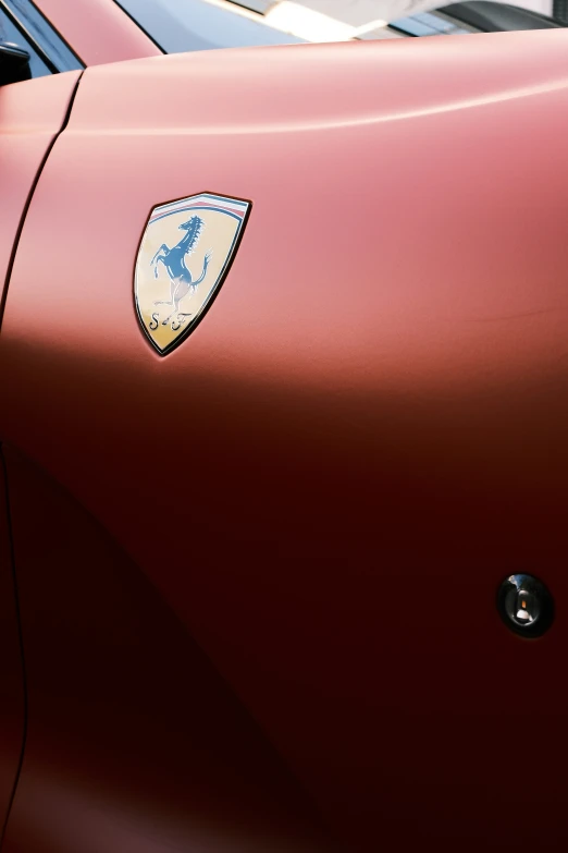 the side of a red car with a yellow ferrari badge on it