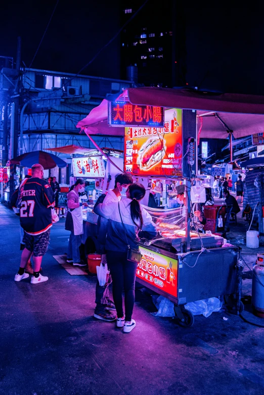 people stand on the street at night near food cart