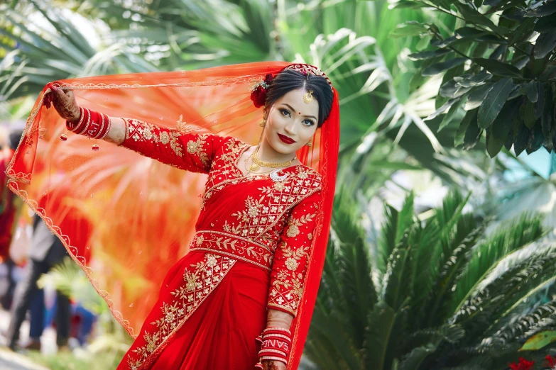 woman in red attire and orange veil holding onto a canopy