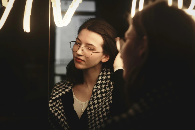 a woman with glasses looking in the mirror