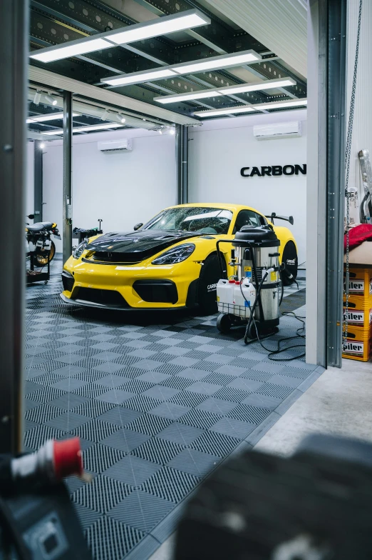 a man in a garage with a yellow car