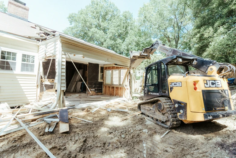 an excavator moves across the dirt in a house's driveway