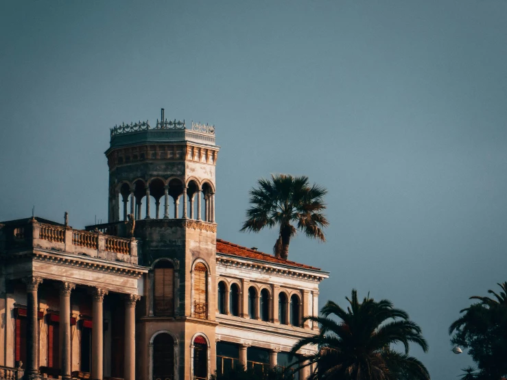 the old tower on the building has some palm trees