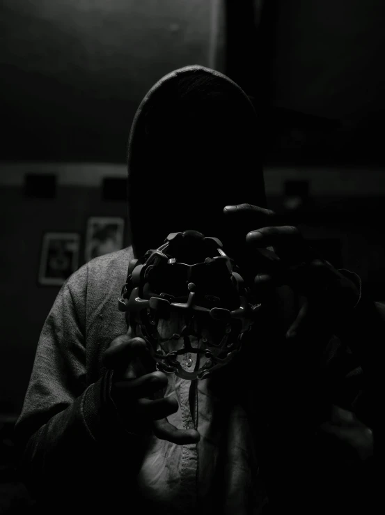 a man wearing a hoodie is holding a strange object in his hands