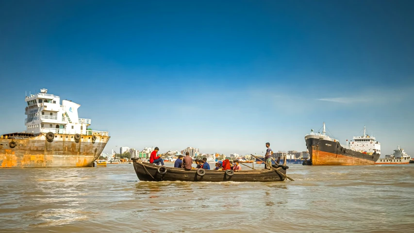 a group of people are in a boat with a large ship