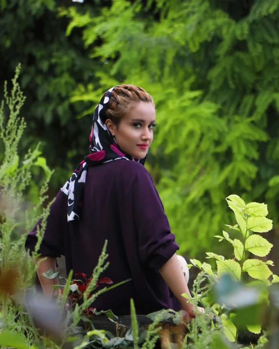 a woman is sitting in the forest and looking around