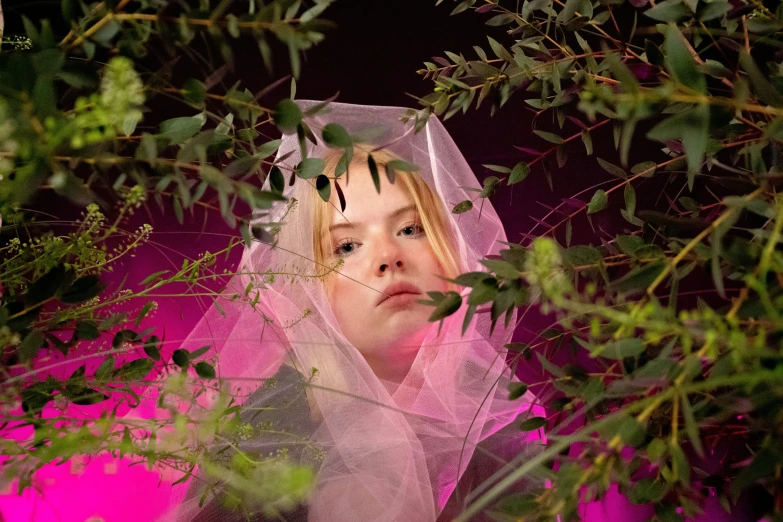 a girl dressed in white with a veil standing under some trees