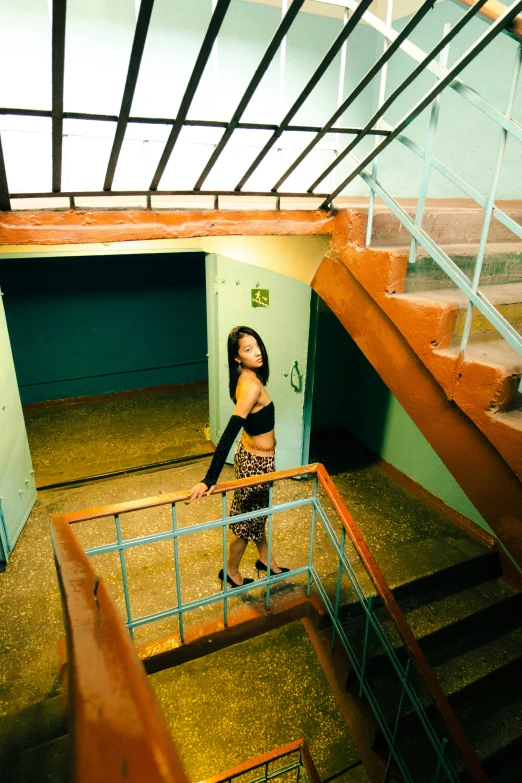 a woman stands at the top of a staircase with her arms behind her head