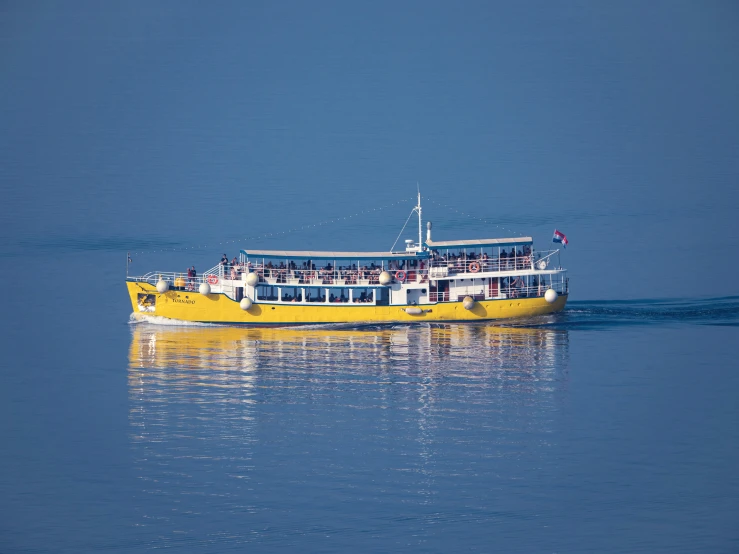 a yellow boat with passengers floating in the ocean