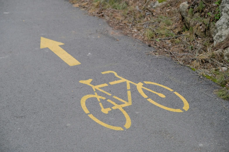 a bike path with yellow painted lines in the pavement
