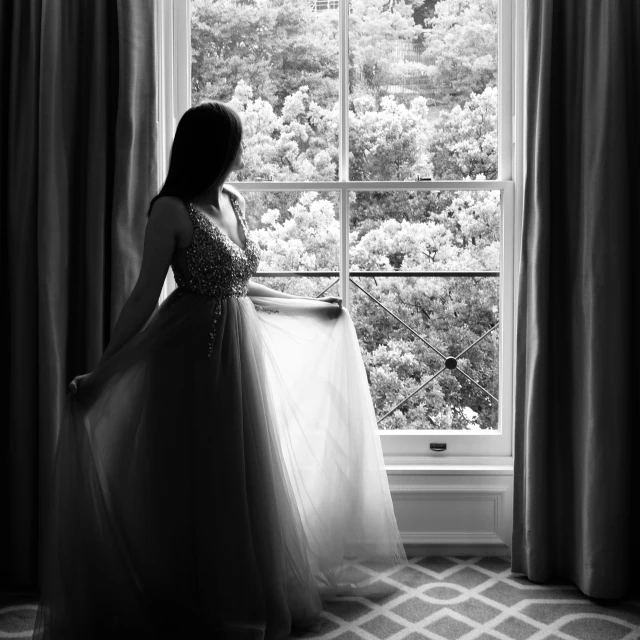 woman wearing wedding gown, looking out window