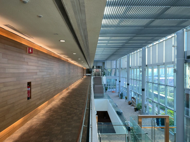 a glass paneled hallway leading up to an atrium