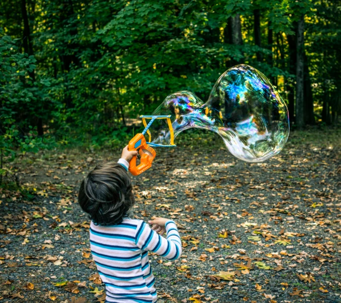 the small child holds a large bubble shaped object